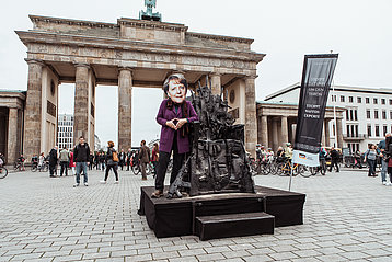 Berlin vor dem Brandenburger Tor: "Merkel" vor dem „Waffenthron“, bestehend aus Nachbildungen von Kleinwaffen